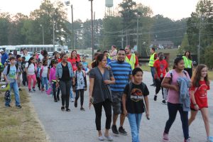 Children and adults walk together.