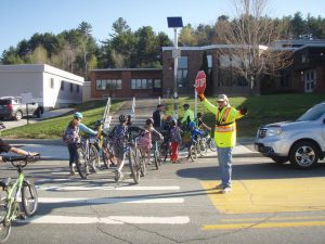 Children walk bikes across crosswalk.