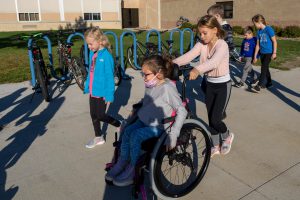 student pushing another student in a wheelchair