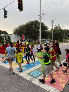 A group of children and adults walk across a colorful crosswalk.